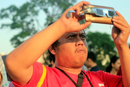 Seorang warga Jakarta tengah bereksperimen memoto gerhana bulan total dengan kaca mata 3D yang ditem