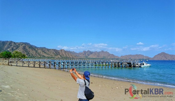Seorang turis selfie di dekat dermaga kayu di Pulau Komodo. Dermaga ini hanya bisa disandarkan perah
