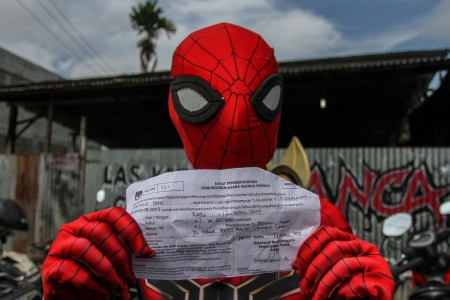 Warga yang mengenakan kostum Spider-Man memperlihatkan surat pemberitahuan pemungutan suara sebelum mencoblos di TPS 01 Kelurahan Pematang Kapau, Kecamatan Tenayan Raya, Pekanbaru, Riau (Foto: Antara)